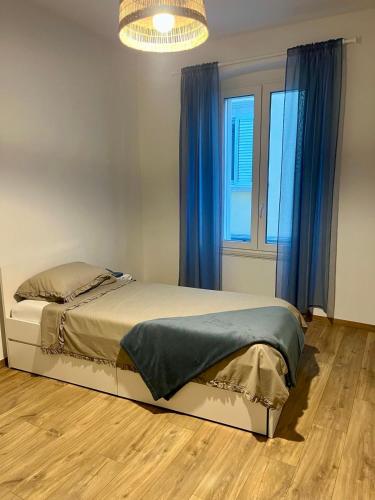 a bedroom with a bed with blue curtains and a chandelier at Collie’s place in Koper