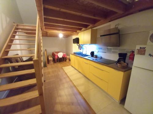 une cuisine avec des armoires jaunes et un escalier dans une pièce dans l'établissement Via Lactéa, à Saint-Goussaud