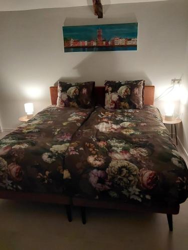 a bedroom with a bed with a floral bedspread at Schuurtje bij de IJssel in Terwolde