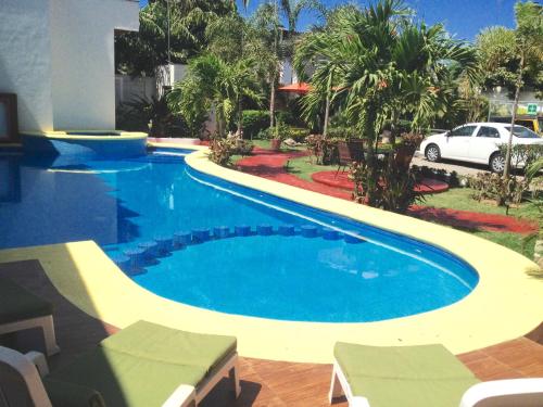 沙由利達的住宿－Hotel y Suites Los Encantos，一个带汽车的院子内的一个大型游泳池