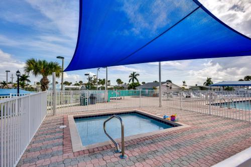 a swimming pool with a blue umbrella over it at Pool and Hot Tub Access Home in Jensen Beach! in Jensen Beach