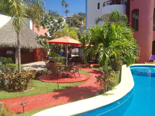 a patio with a table and umbrella next to a pool at Hotel y Suites Los Encantos in Sayulita