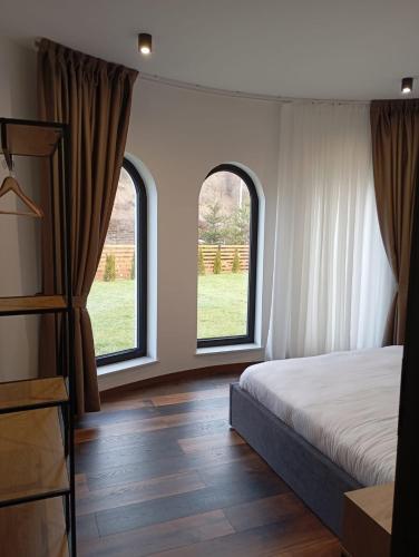 a bedroom with two windows and a bed and wooden floors at Julien House in Prisaca Dornei