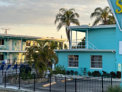 a blue house with palm trees in front of it at Sea Jay Motel and Marina in St Pete Beach
