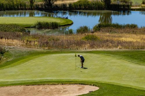 a man holding a golf club on a golf course at Alpine Retreat at the Pointe Pt A106 in Eden