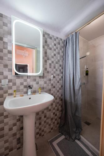 a bathroom with a sink and a shower with a mirror at Aphrodites Apartments in Kini
