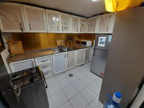 a kitchen with white cabinets and a sink and a refrigerator at Adbldna01 in Abu Dhabi