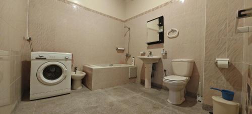 a bathroom with a toilet sink and a washing machine at Bel appartement familial au centre ville in El Kelaa des Srarhna