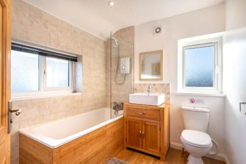 a bathroom with a tub and a toilet and a sink at Port View House 3-Bedroom Self Catering Family Home with Garden Near Cardiff in Cardiff