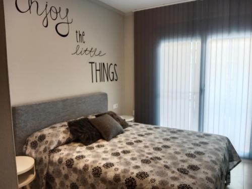 a bedroom with a bed and a sign that says enjoy its little things at Piso con piscina y parking in Peñíscola