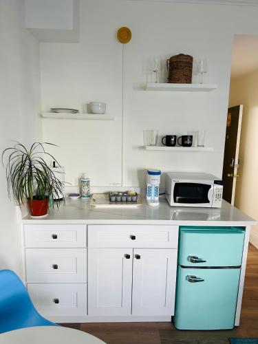 a kitchen with white cabinets and a blue refrigerator at Romantic Studio in the Heart of Palm Beach in Palm Beach