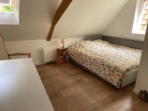 Un dormitorio con una cama y suelo de madera. en l'ADRESSE, en Bergues