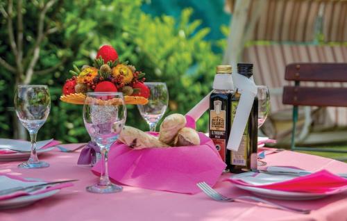 a pink table with a bowl of fruit and wine bottles at Apartments Villa Bare in Kastav