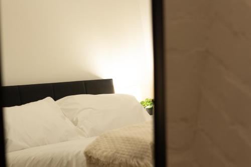a bedroom with a bed with white sheets and a mirror at Stylish Cosy 4-Bed Home, Sleeps Up To 10 With Large Sofa Bed, Near Manchester Royal Infirmary & Universities, Free Parking & Ultra-Fast WiFi in Manchester