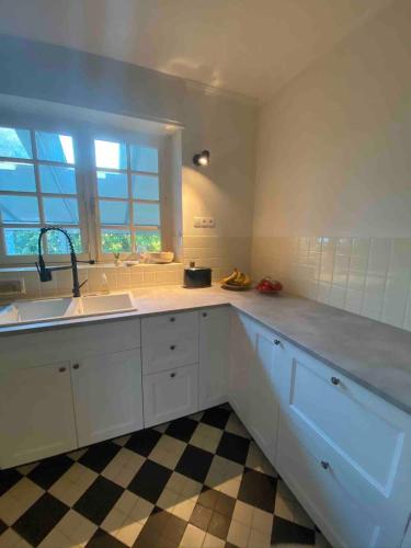 une cuisine avec des armoires blanches, un évier et une fenêtre dans l'établissement MaisonPortManech - exquisites Kleinod in der Bretagne, à Névez
