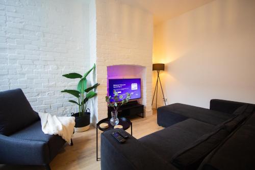 a living room with a couch and a tv at Stylish Cosy 4-Bed Home, Sleeps Up To 10 With Large Sofa Bed, Near Manchester Royal Infirmary & Universities, Free Parking & Ultra-Fast WiFi in Manchester