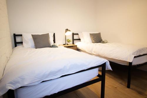 two beds in a room with white sheets at Stylish Cosy 4-Bed Home, Sleeps Up To 10 With Large Sofa Bed, Near Manchester Royal Infirmary & Universities, Free Parking & Ultra-Fast WiFi in Manchester