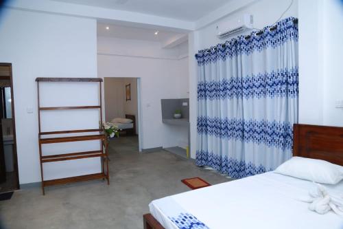 a bedroom with a bed and a blue and white curtain at ABR Ahangama Beach Resort in Ahangama