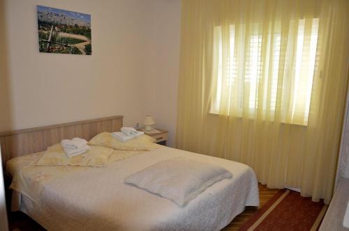 a bedroom with a bed with white sheets and a window at Apartments Zdravko in Orebić