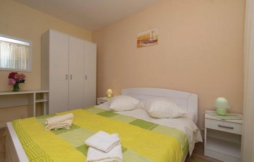Schlafzimmer mit einem Bett mit gelber Bettwäsche und weißen Kissen in der Unterkunft Apartments Zdravko in Orebić