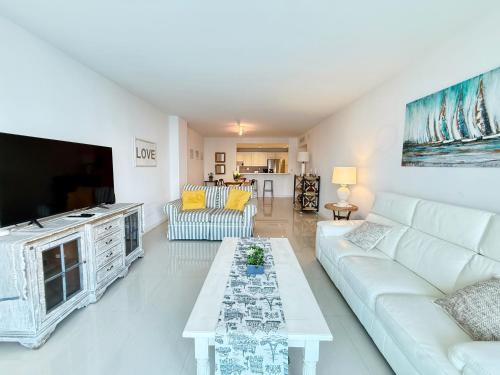 a living room with a white couch and a tv at 1 SPRING PROMO - Sunny Isles Seaview Condo, Walk to Beach, Amazing Amenities in Sunny Isles Beach