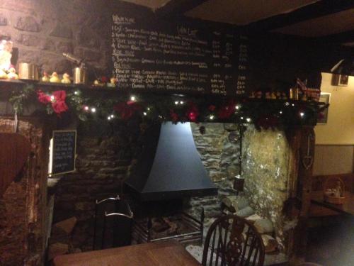 a bar with a stone fireplace with christmas lights at Plume of Feathers in Blagdon