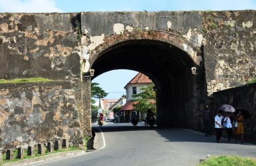 an arch in a stone wall with people walking under it at Orchard House Galle in Galle