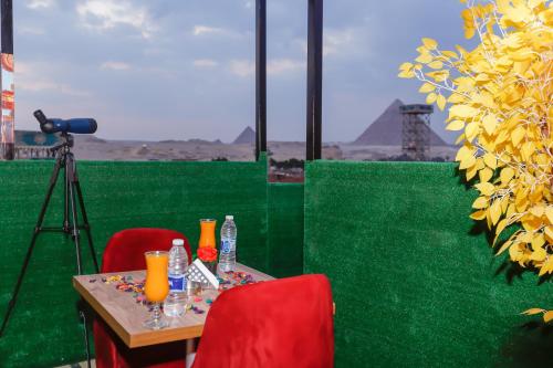 een tafel met twee rode stoelen en een camera bij Paradise Pyramids View INN in Caïro