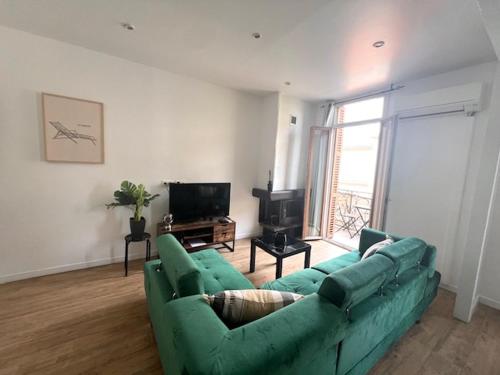 un salon avec un canapé vert et une télévision dans l'établissement Appartement cosy centre ville NICE, à Nice