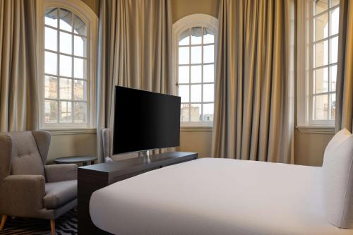 a bedroom with a bed and a tv and a chair at Doubletree by Hilton Edinburgh City Centre in Edinburgh
