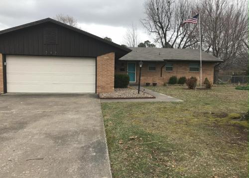 a house with a garage and an american flag at Entire House in the Heart of NW AR with Office Space in Springdale