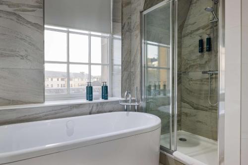 a bathroom with a tub and a shower and a window at Doubletree by Hilton Edinburgh City Centre in Edinburgh