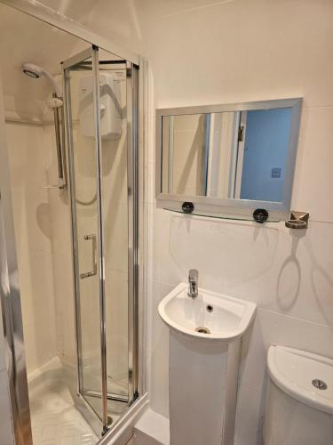 a white bathroom with a shower and a sink at Mirandas Place in Gillingham