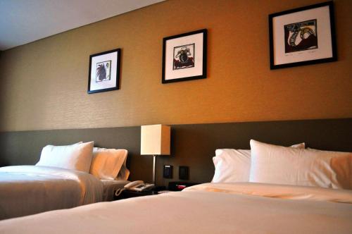 two beds in a hotel room with pictures on the wall at Hilton Garden Inn Tucuman in San Miguel de Tucumán