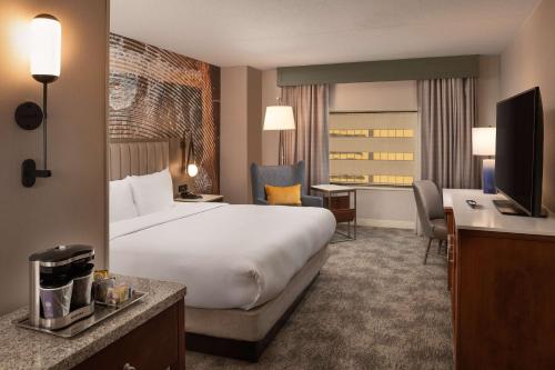 a hotel room with a large bed and a television at Hilton Lexington Downtown in Lexington