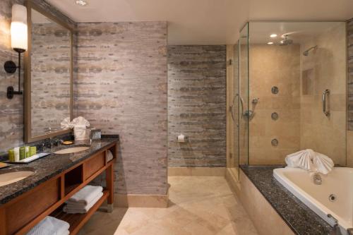 a bathroom with two sinks and a tub and a shower at Hilton Lexington Downtown in Lexington