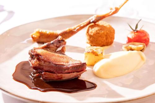 a plate of food with a piece of meat and sauce at Chateau des Ducs de Joueuse, BW Signature Collection in Couiza