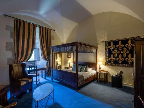 a bedroom with a large canopy bed and a chair at Chateau des Ducs de Joueuse, BW Signature Collection in Couiza