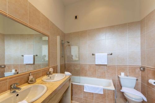 a bathroom with two sinks and a toilet and a mirror at Chateau des Ducs de Joueuse, BW Signature Collection in Couiza