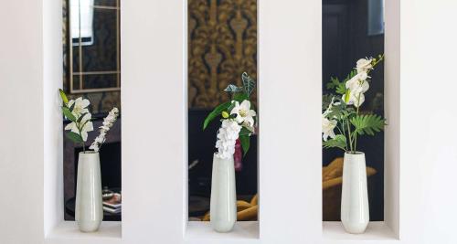 a group of white vases with flowers in them at Best Western Plus Le Picardy in Saint-Quentin
