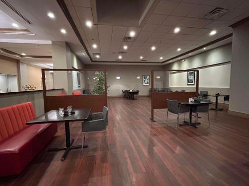 a waiting room with a red couch and tables at Skyline Hotel Detroit Airport, SureStay Collection by Best Western in Romulus