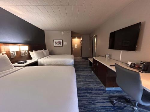a hotel room with two beds and a desk at Skyline Hotel Detroit Airport, SureStay Collection by Best Western in Romulus