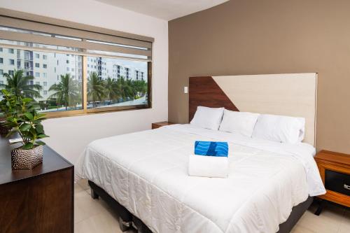 a bedroom with a large white bed with a window at Magnifico con amenidades únicas in Cancún