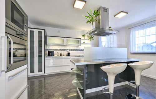 eine Küche mit weißen Schränken und einer Theke mit Stühlen in der Unterkunft 2 Bedroom Amazing Home In Bjelovar in Bjelovar