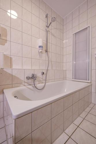 a white bath tub in a white tiled bathroom at Apartment 4 in Bad König