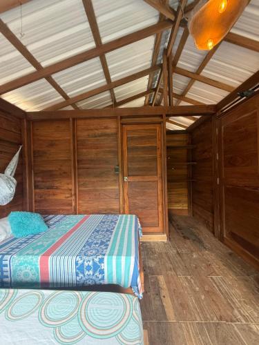 a bedroom with a bed in a room with wooden walls at La Bamba in Termales - agua caliente - nuqui