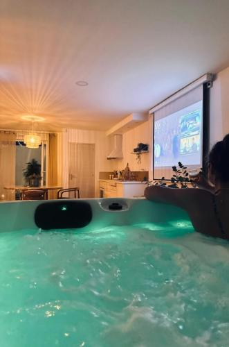 une femme se posant au bord d'une piscine avec une télévision dans l'établissement À 4 minutes de la plage, avec Jacuzzi et Sauna, à Outreau