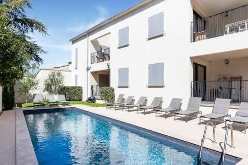 une piscine avec des chaises et un bâtiment dans l'établissement Résidence Les Cyclistes, appartement La Musette, à Malaucène