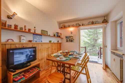 a dining room with a table and a tv at Appartamento La Marmotta Mountain Retreat - Happy Rentals in Claviere
