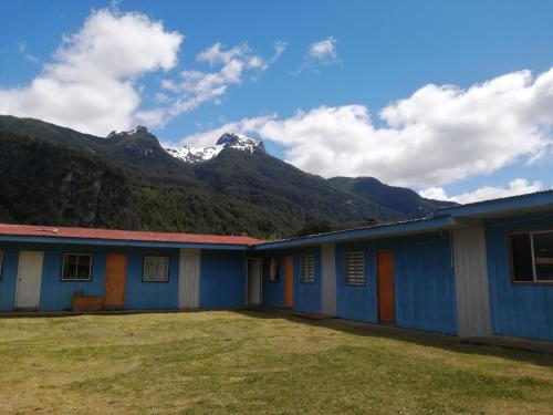 un bâtiment bleu avec des montagnes en arrière-plan dans l'établissement Refugio Amelia, à Villa Maniguales